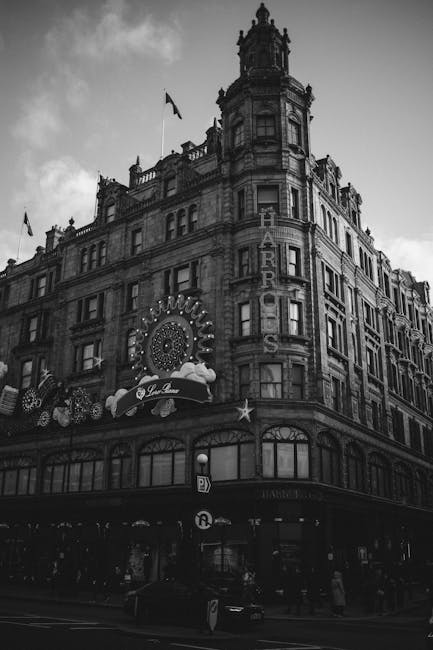 A busy street scene in Knightsbridge featuring a historic building with ornate architectural details and a prominent Harrods sign illuminated on the facade. The building has a large dome at the top an